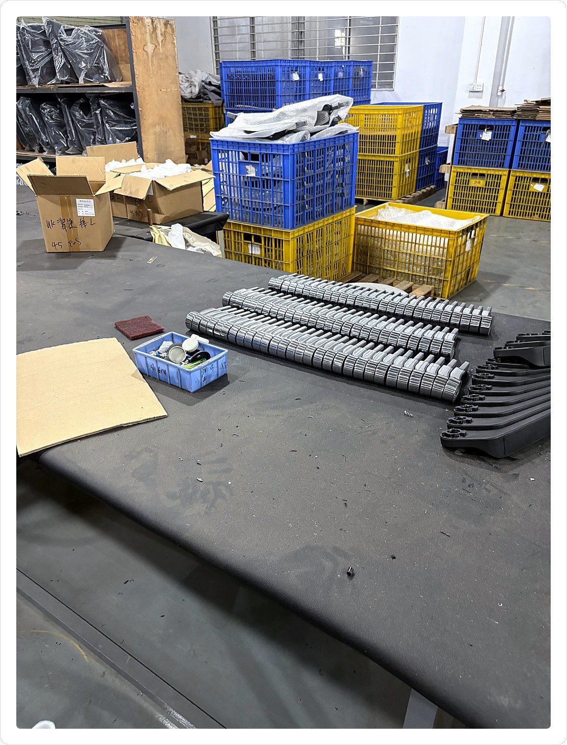 Rows of armrest sub-assemblies staged on a fitting bench with hardware bins alongside